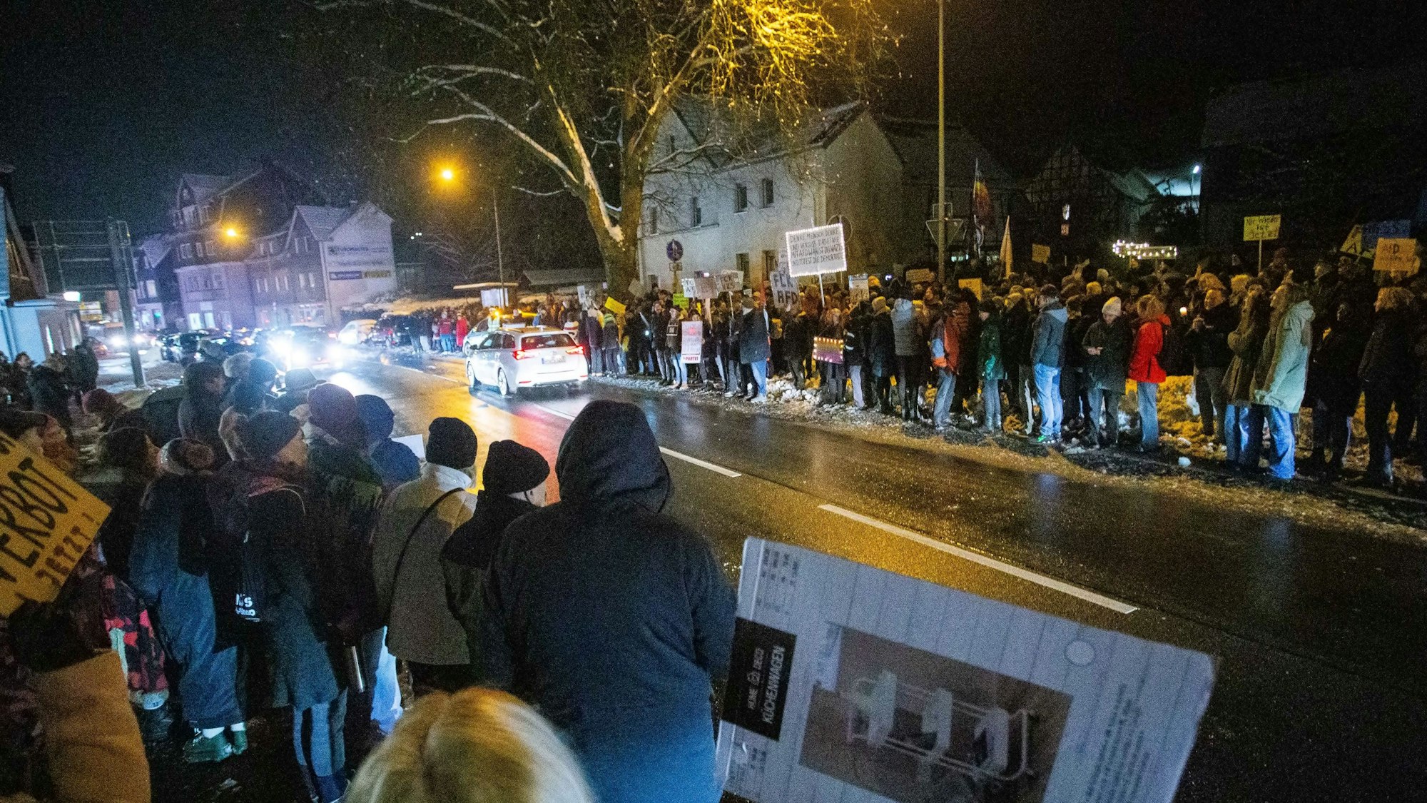Menschen mit Transparenten stehen an einer Straße.