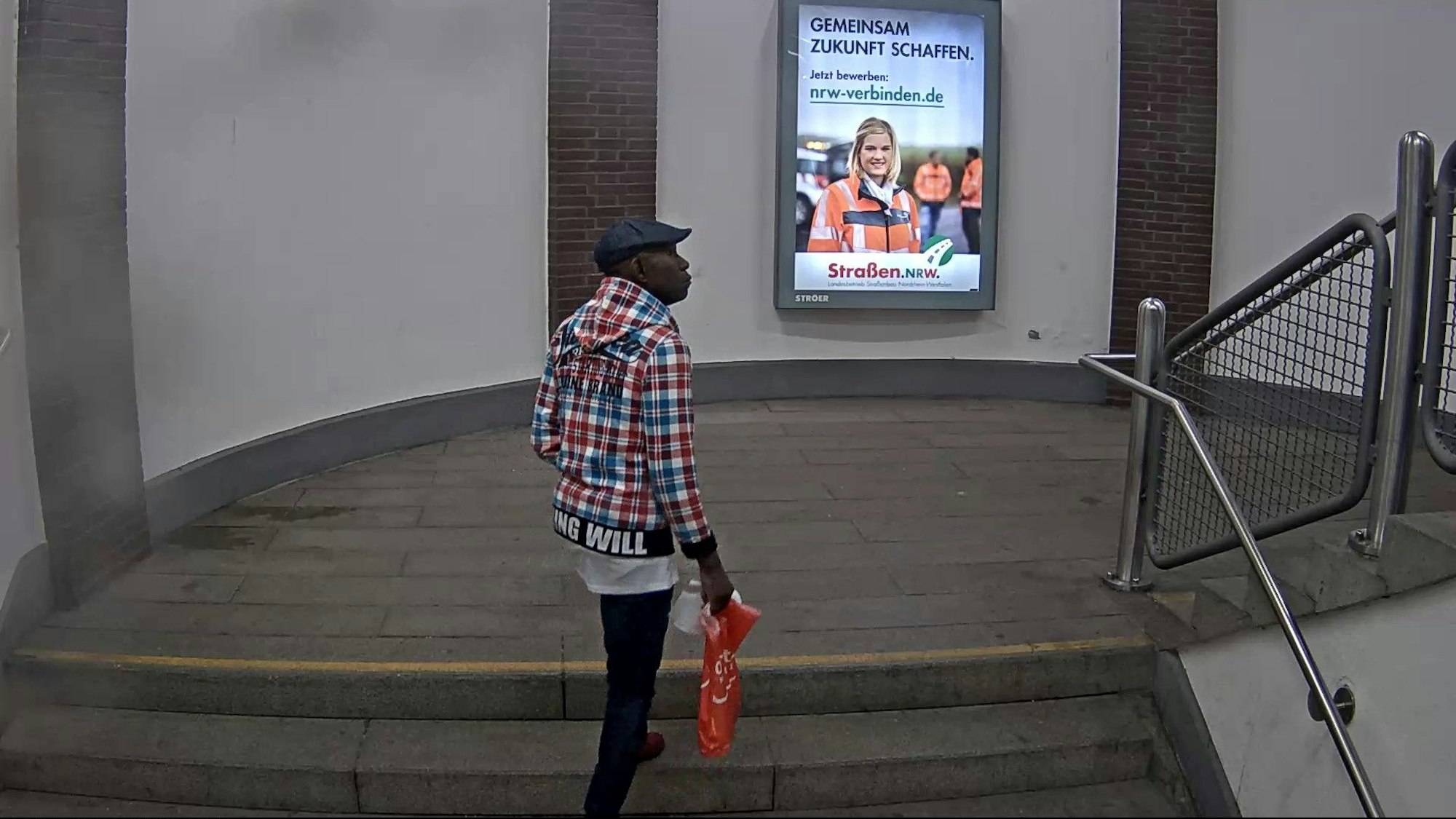 Ein Mann in einem bunt karierten Hemd geht durch den Bahnhof Köln-Deutz/Messe.