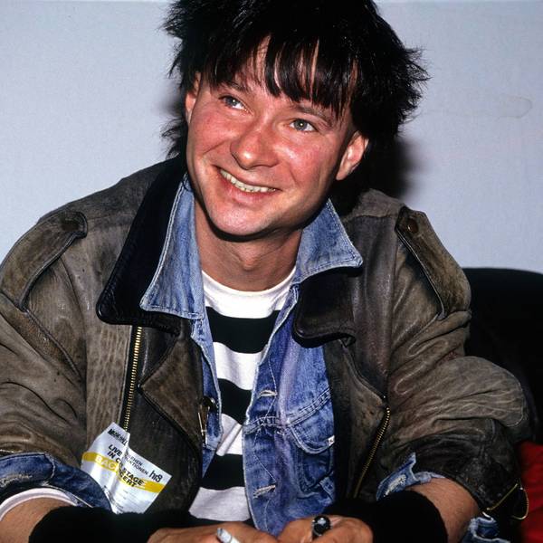 Frank Ziegert von der Hamburger Band Abwärts sitzt auf einem schwarzen Sofa. Er trägt eine alte Lederjacke über einer Jeansjacke, seine Haare sind schwarzgefärbt.