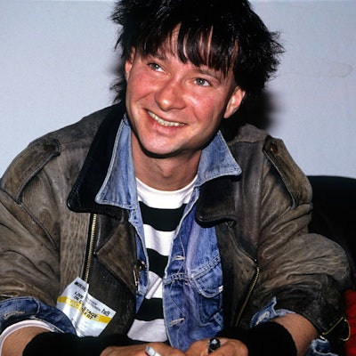 Frank Ziegert von der Hamburger Band Abwärts sitzt auf einem schwarzen Sofa. Er trägt eine alte Lederjacke über einer Jeansjacke, seine Haare sind schwarzgefärbt.