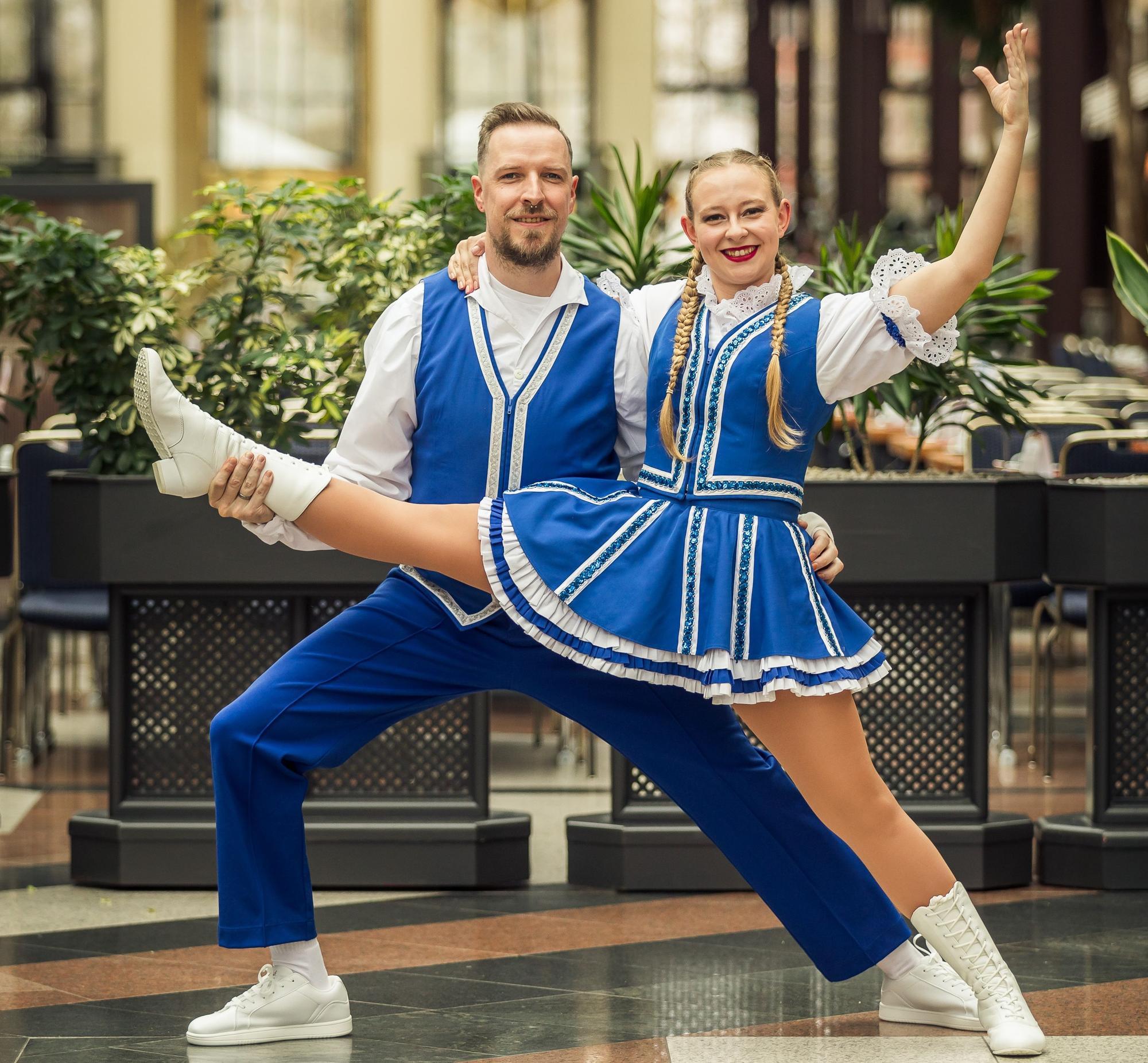 Ein Tanzpaar in blau-weißem Outfit posiert vor dem Kamera.