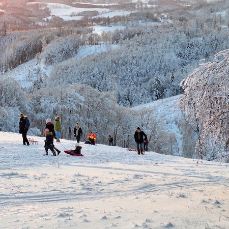 Ein Blick auf die weiße Landschaft mit Rodlern im Vordergrund.