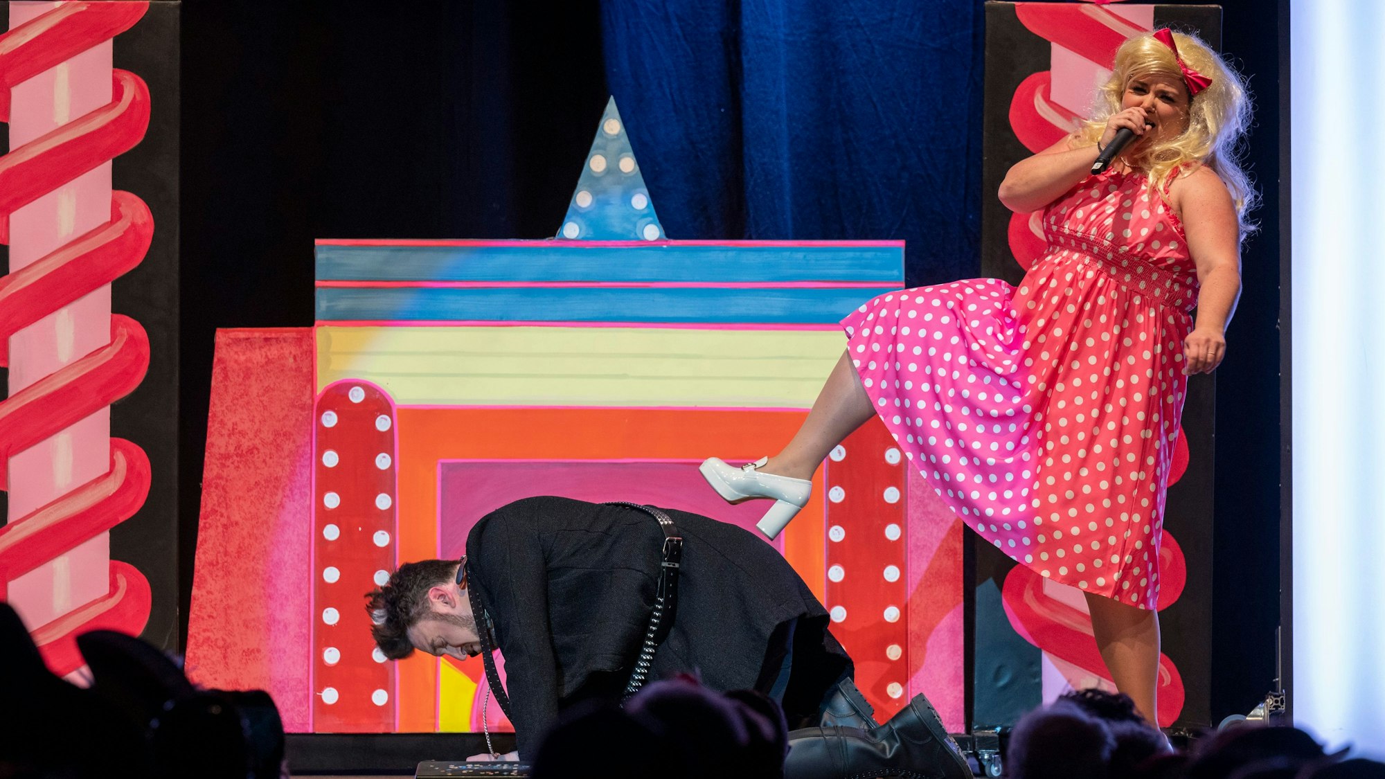 Eine als Barbie verkleidete Frau drückt ihren Fuß auf einen am Boden hockenden als Till Lindemann verkleideten Mann.