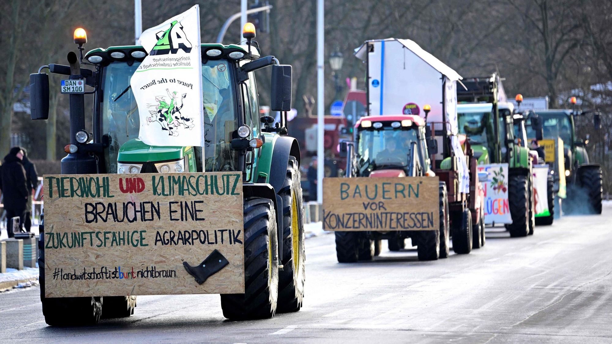 Farmers with their tractors drive near the Reichstag building during a protest under the title 'We are fed up with agricultural industry' against industrial food production in Berlin, Germany on January 20, 2024. The lettering on the board left reads 'Animal welfare and climate protection need a sustainable agricultural policy'. The demonstration started on January 20 in front of the headquarters of German Social Democratic Party SPD and ended with a rally in front of the Chancellery. (Photo by Tobias SCHWARZ / AFP)