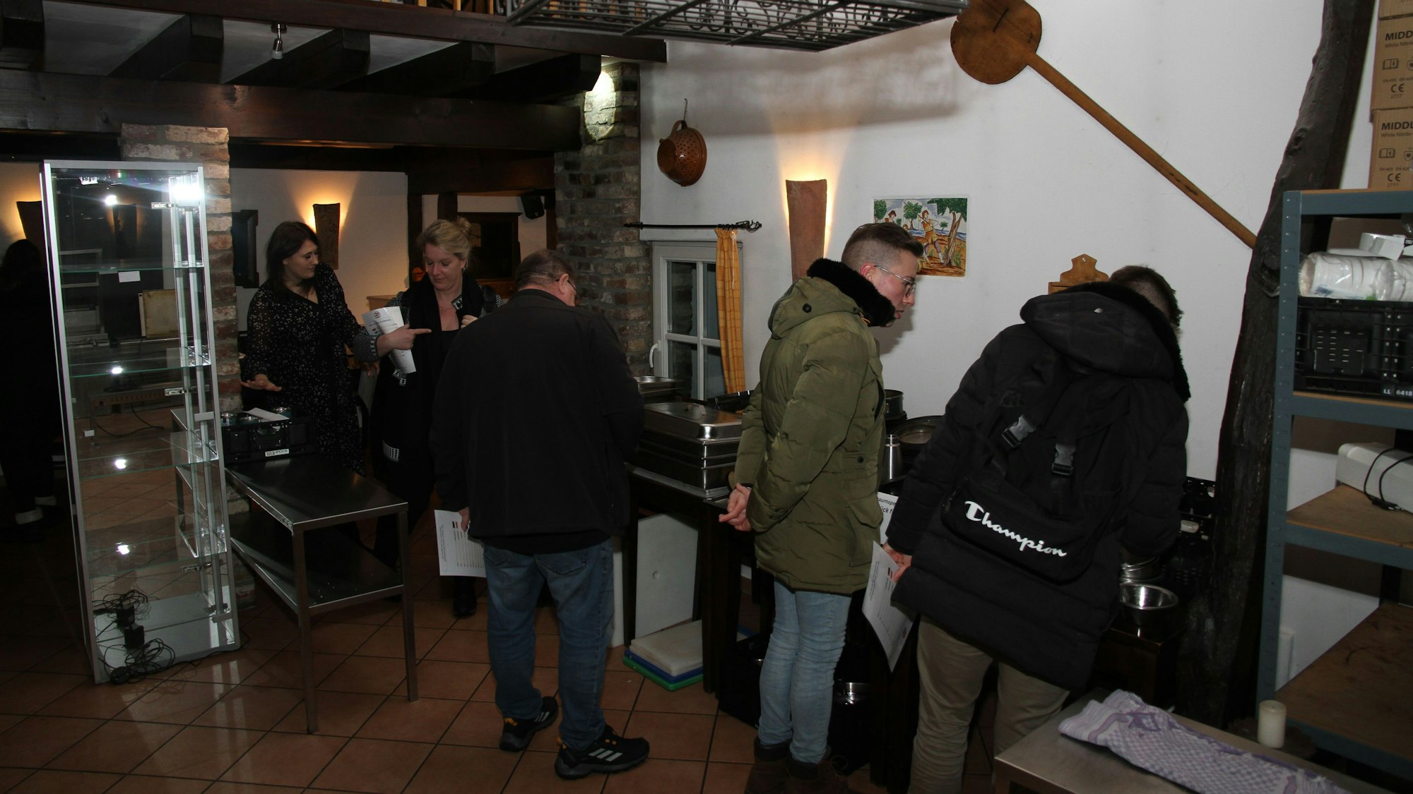 Zwei Frauen und drei Männer sehen sich zum Verkauf stehende Gegenstände in einem Fachwerkhaus an