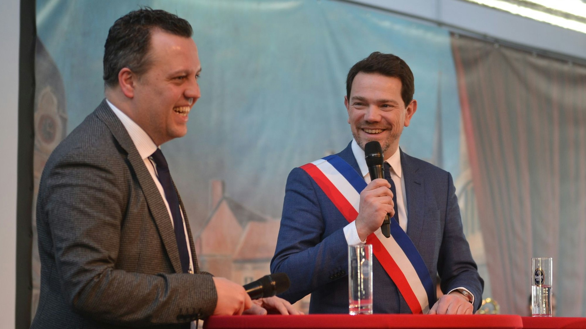 Die beiden Bürgermeister am Rednerpult. Der französische Bürgermeister trägt eine Schärpe in den französischen Nationalfarben.