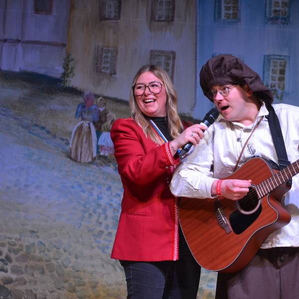 Robert Becker spielt auf der Bühne Gitarre und singt dazu, Birte Karstens hält für ihn das Mikrofon.