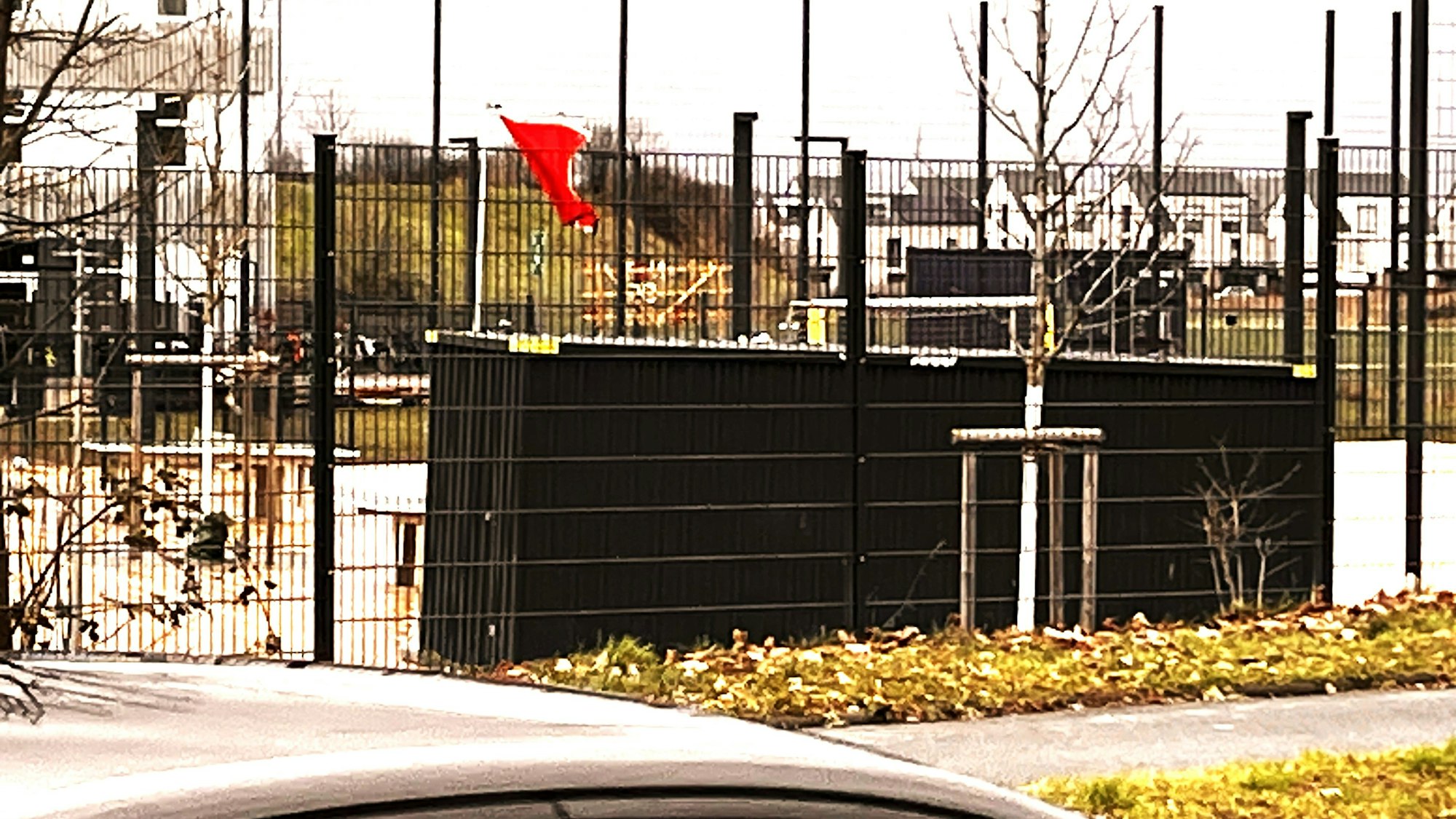 Eine rote Fahne weht auf einem eingezäunten Schulhof.