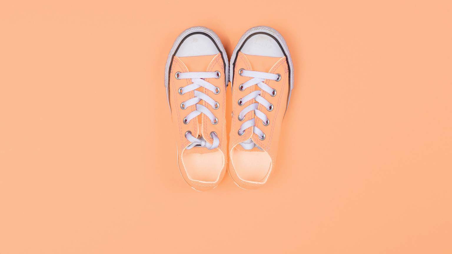 Sneaker von oben vor einem pfirsichfarbenen Hintergrund