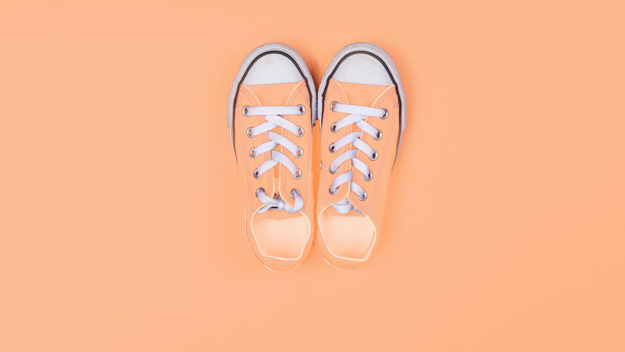 Sneaker von oben vor einem pfirsichfarbenen Hintergrund