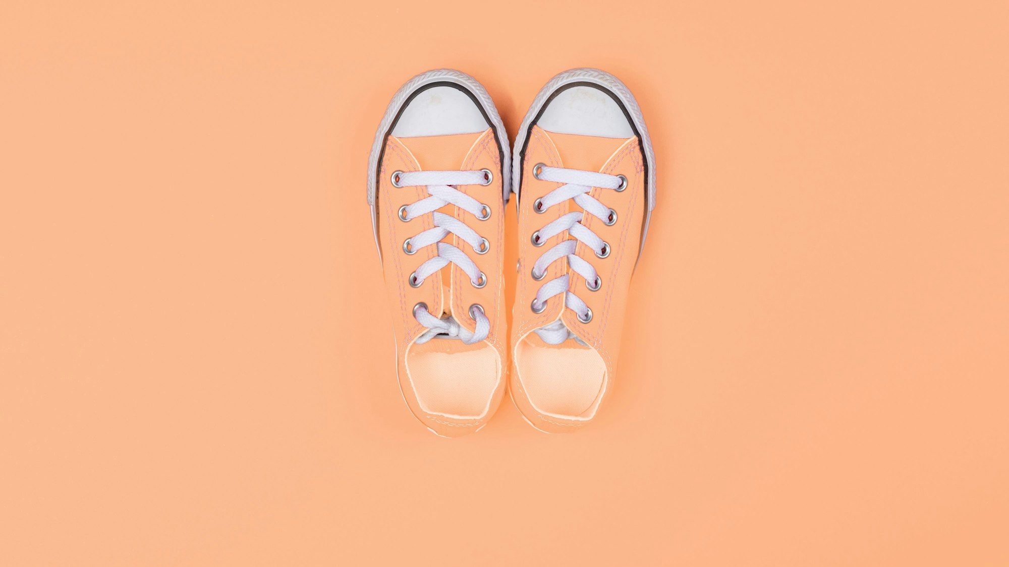 Sneaker von oben vor einem pfirsichfarbenen Hintergrund