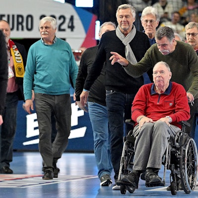 In seinem Rollstuhl, geschoben von Heiner Brand, führt Jo Deckarm die 78er Weltmeister in der Lanxess-Arena an.