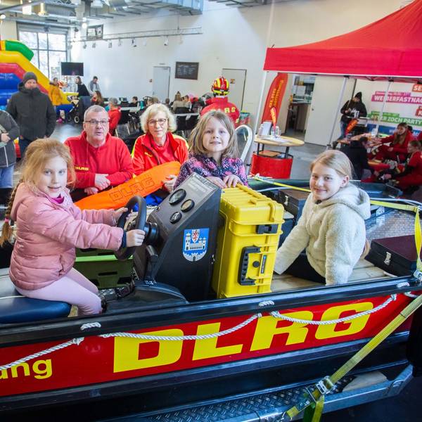 Das Foto zeigt das Rettungsboot der DLRG Wipperfürth mit drei Kindern und Ehrenamtlern der DLRG im Hintergrund.