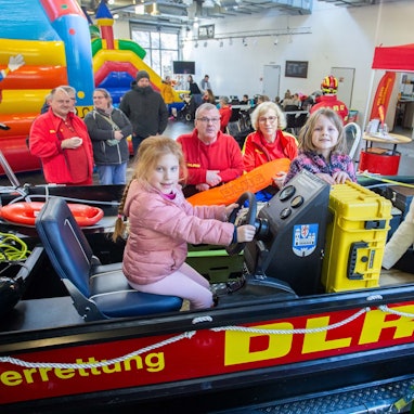 Das Foto zeigt das Rettungsboot der DLRG Wipperfürth  mit drei Kindern und Ehrenamtlern der DLRG im Hintergrund.