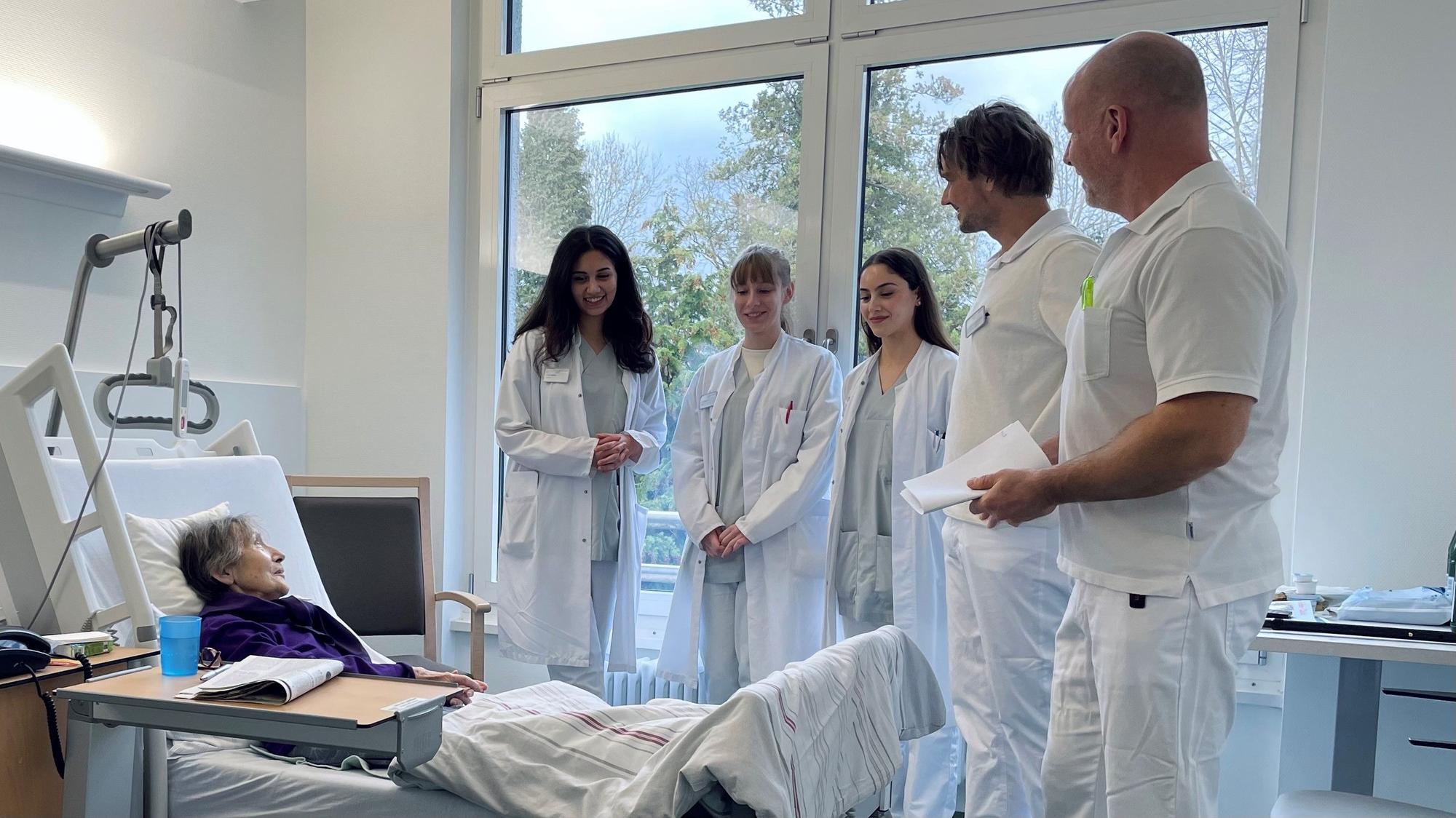 Die Studentinnen Dunya Wahisi, Lynn Hoffmann und Danae Zimboulaki stehen gemeinsam mit den Ärzten Cornelius Jacobs und Sascha Wihstutz um das Bett einer Patientin im St. Remigius Krankenhaus Opladen.