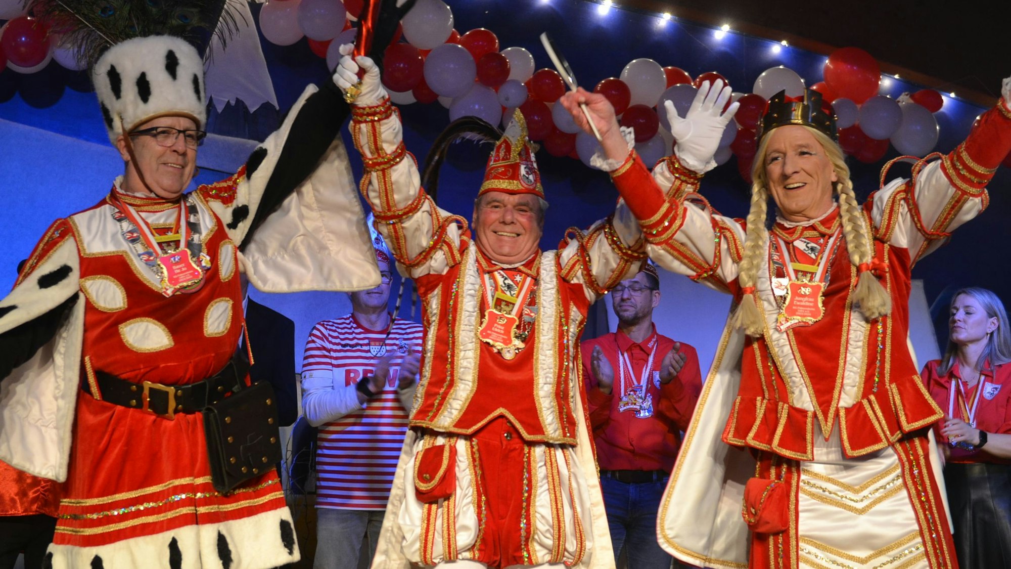 Das kostümierte Palmersheimer Dreigestirn wirft die Arme in die Luft.