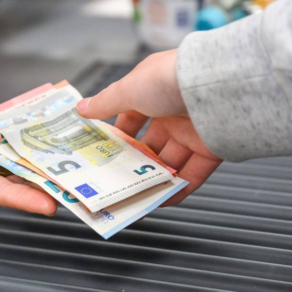 Eine Kassiererin gibt einer Kundin Wechselgeld an der Kasse eines Supermarktes.