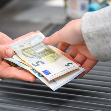 Eine Kassiererin gibt einer Kundin Wechselgeld an der Kasse eines Supermarktes.