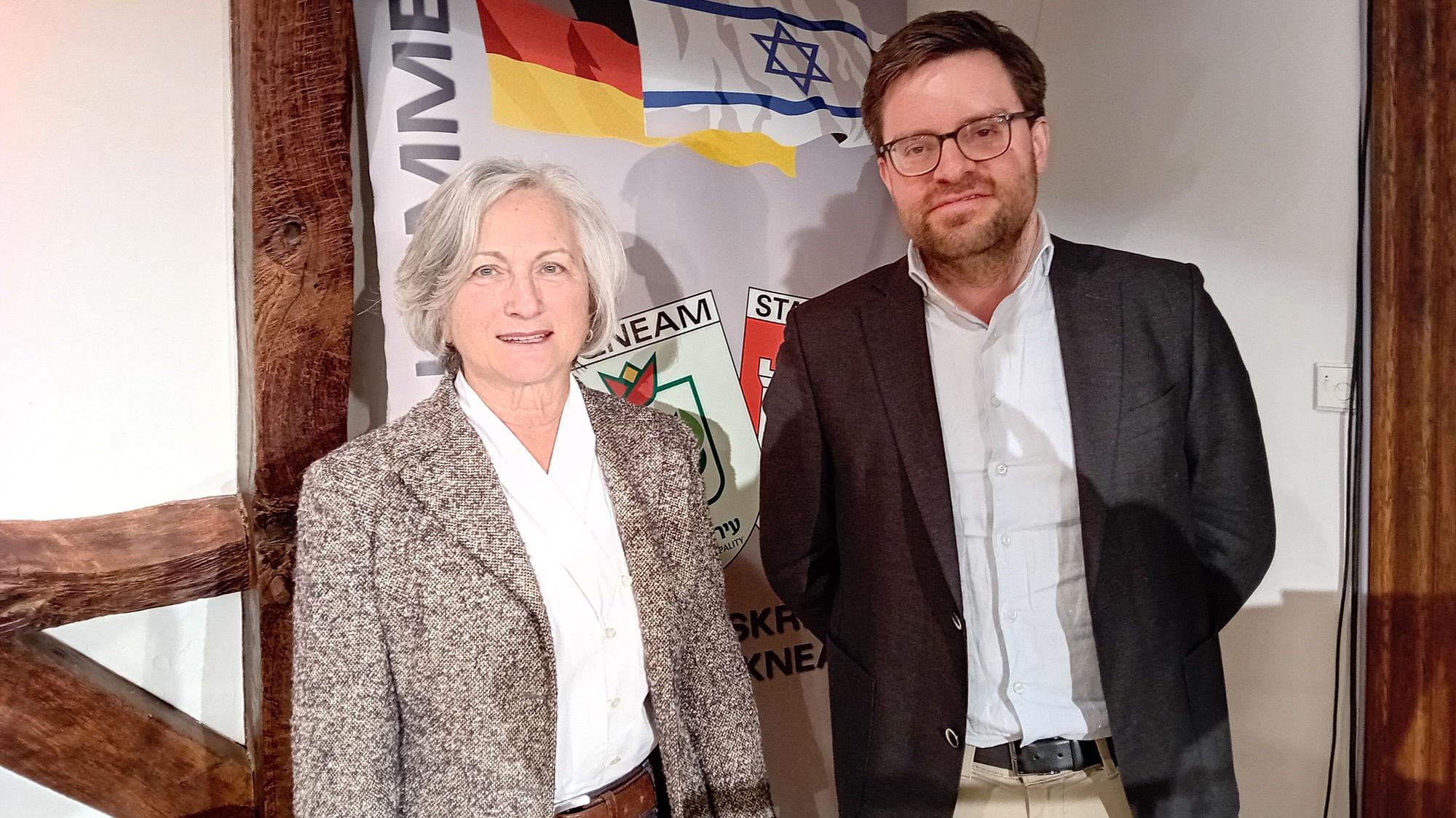 Eine Frau und ein Mann vor einem Transparent.