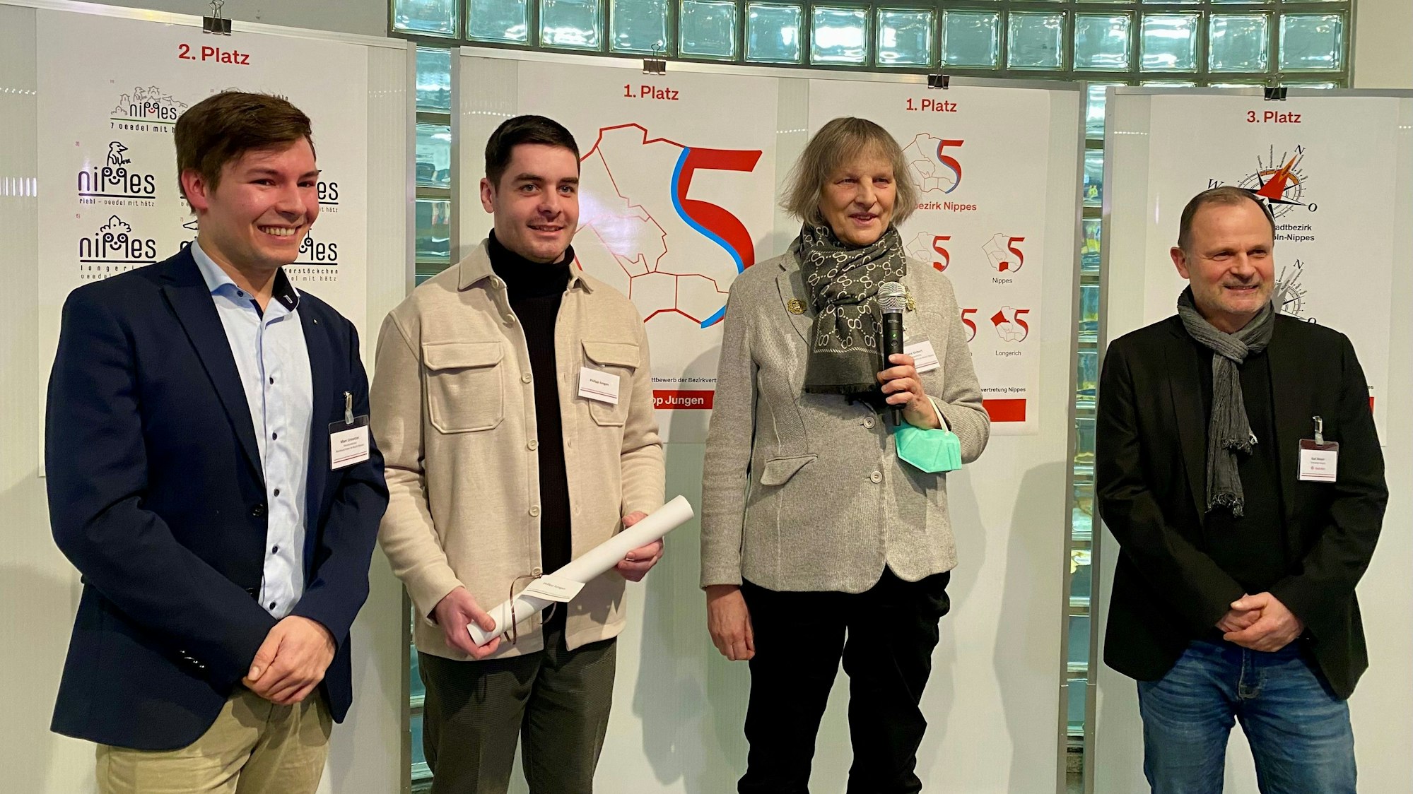 Vier Menschen stehen vor Plakaten.