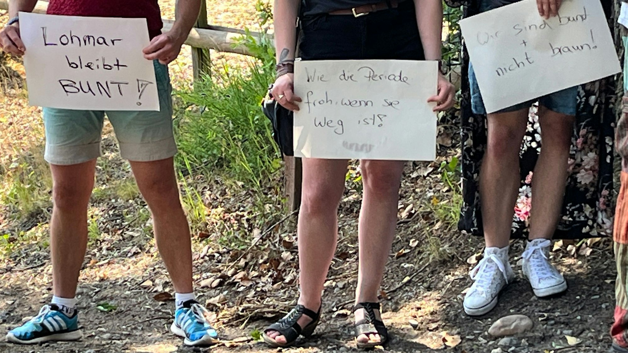 Drei Teilnehmer einer Demo mit Plakaten, die Oberkörper sind nicht im Bild