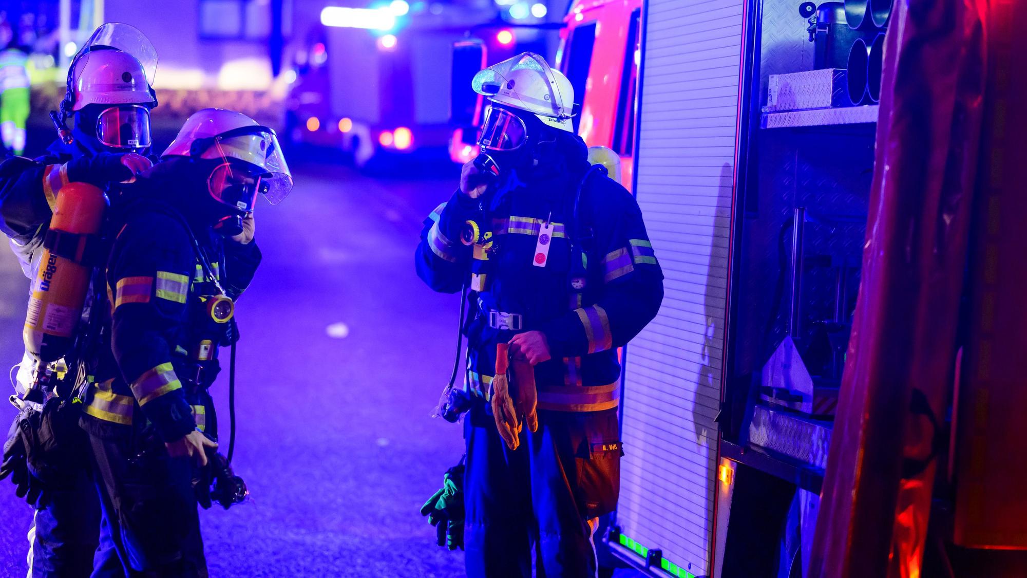 Einsatzkräfte der Feuerwehr legen Atemschutzgeräte an.