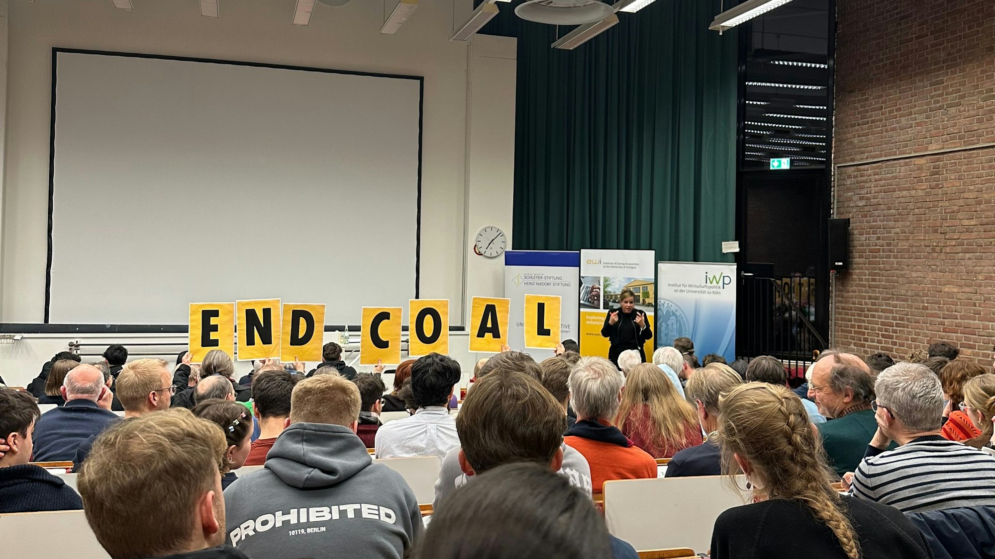 12 Mitglieder von „Scientist Rebellion“ unterbrachen den Vortrag von Mona Neubaur an der Universität zu Köln. Sie hielten dabei ein Banner mit der Aufschrift „Lützerath wurde sinnlos zerstört, Frau Neubaur“ in die Höhe.