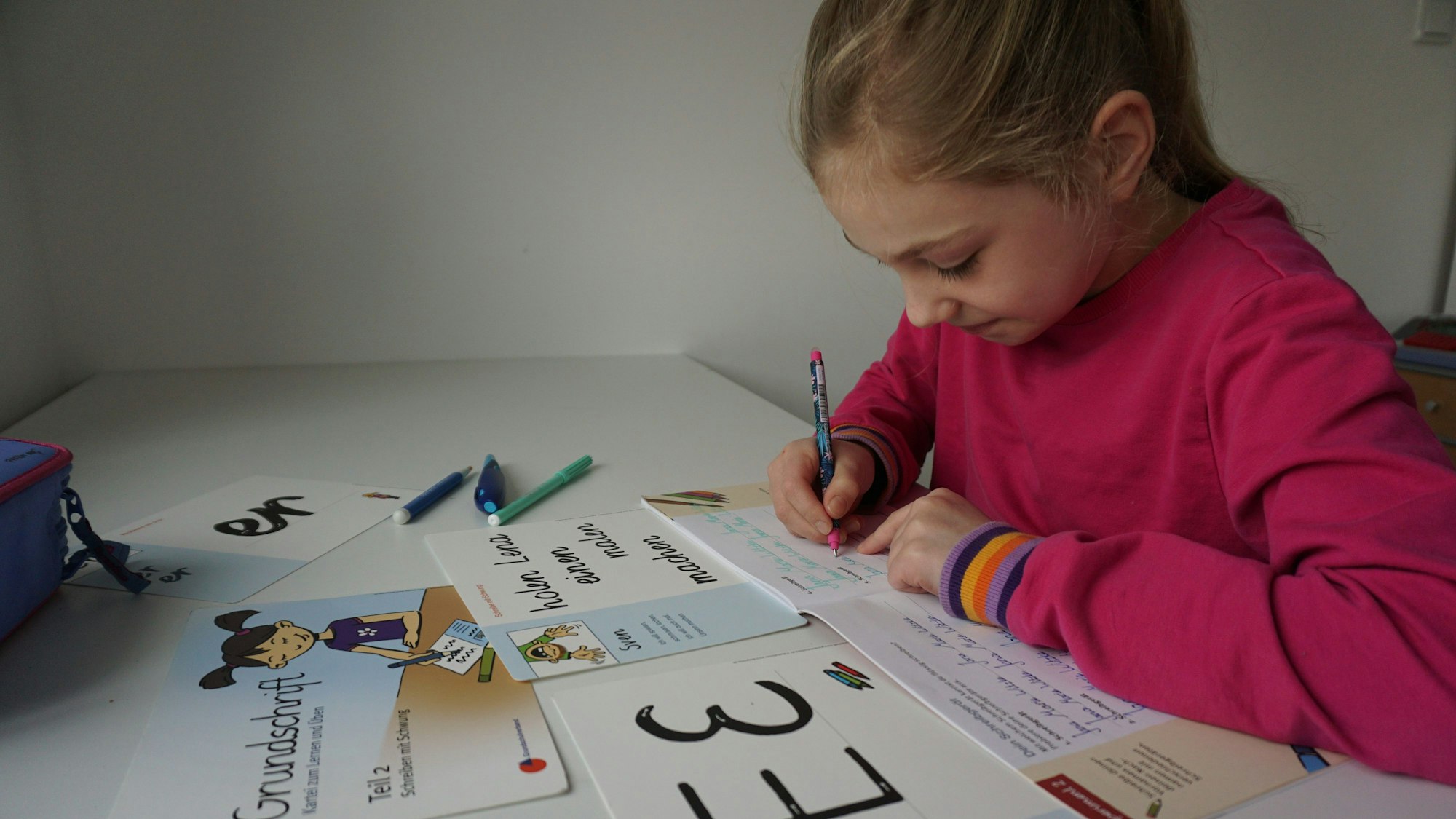 Ein Mädchen schreibt mit einem Stift in ein Heft und konzentriert sich darauf.
