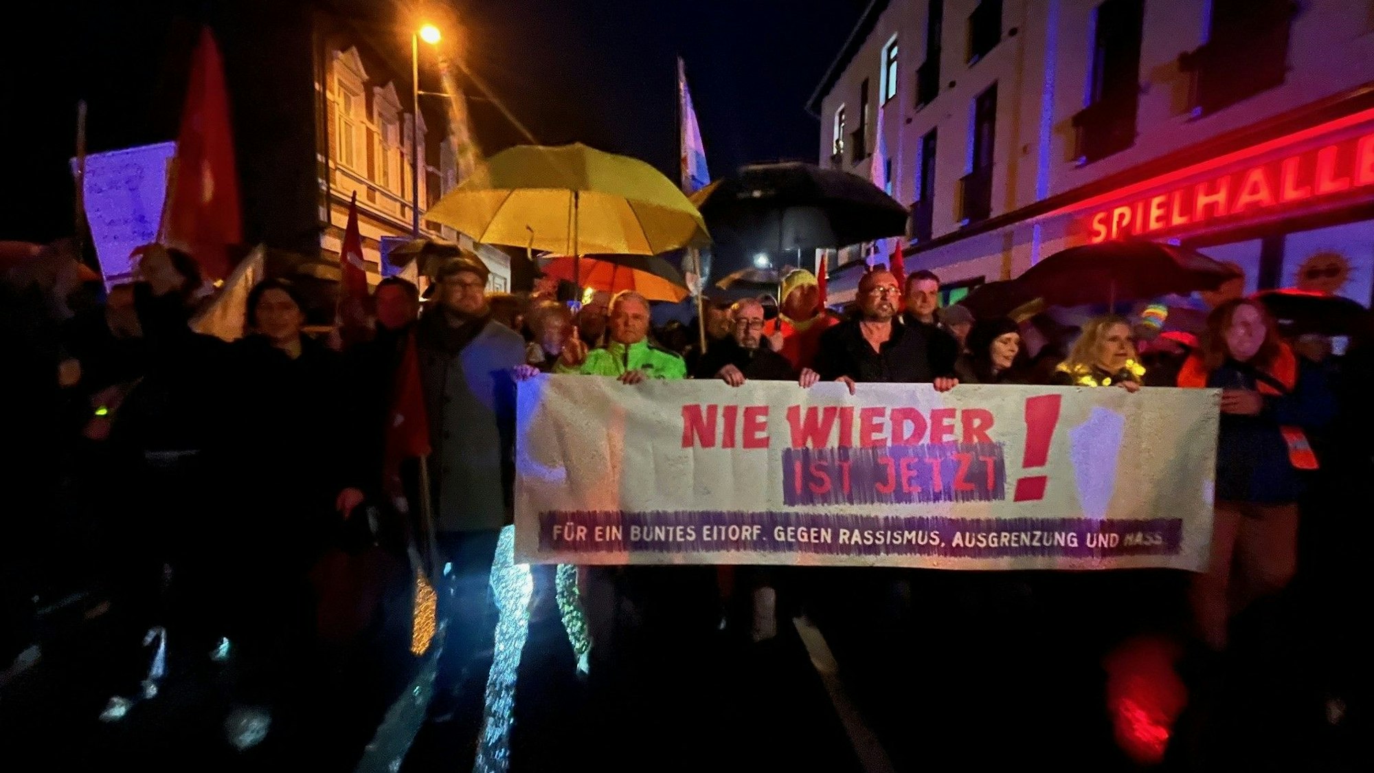 Menschen mit einem großen Plakat gehen einem Demonstrationszug vorweg.