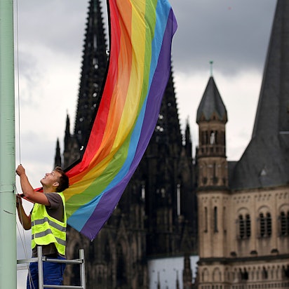 Ein Arbeiter hängt nach der Entscheidung im Bundestag über die «Ehe für alle» vor der Kulisse des Kölner Doms und der Kirche Groß St. Martin (r.) eine Regenbogenfahne auf. Mehr als 200 Theologieprofessoren haben in einer gemeinsamen Stellungnahme gegen das Segnungsverbot des Vatikans für homosexuelle Paare protestiert.
