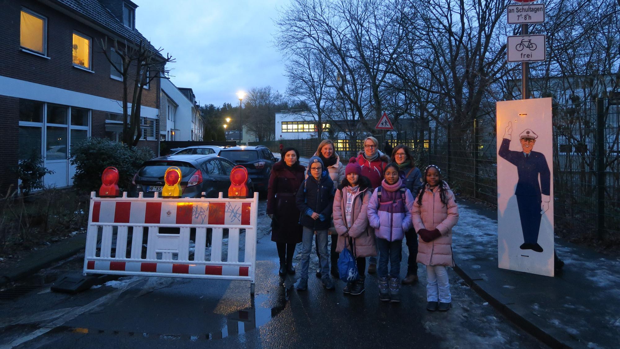 Kinder stehen an einer Straßenabsperrung.