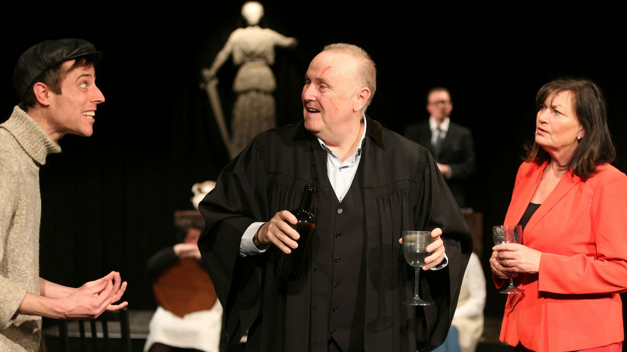 Bühnenszene mit drei Darstellern.