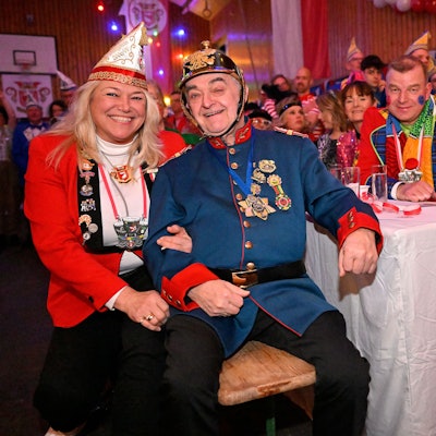 NRW-Innenminister Herbert Reul sitzt mit Tanja Paas vom Festkomitee der Karnevalsfreunde Oberodenthal kostümiert in der Prunksitzung in Oberodenthal.