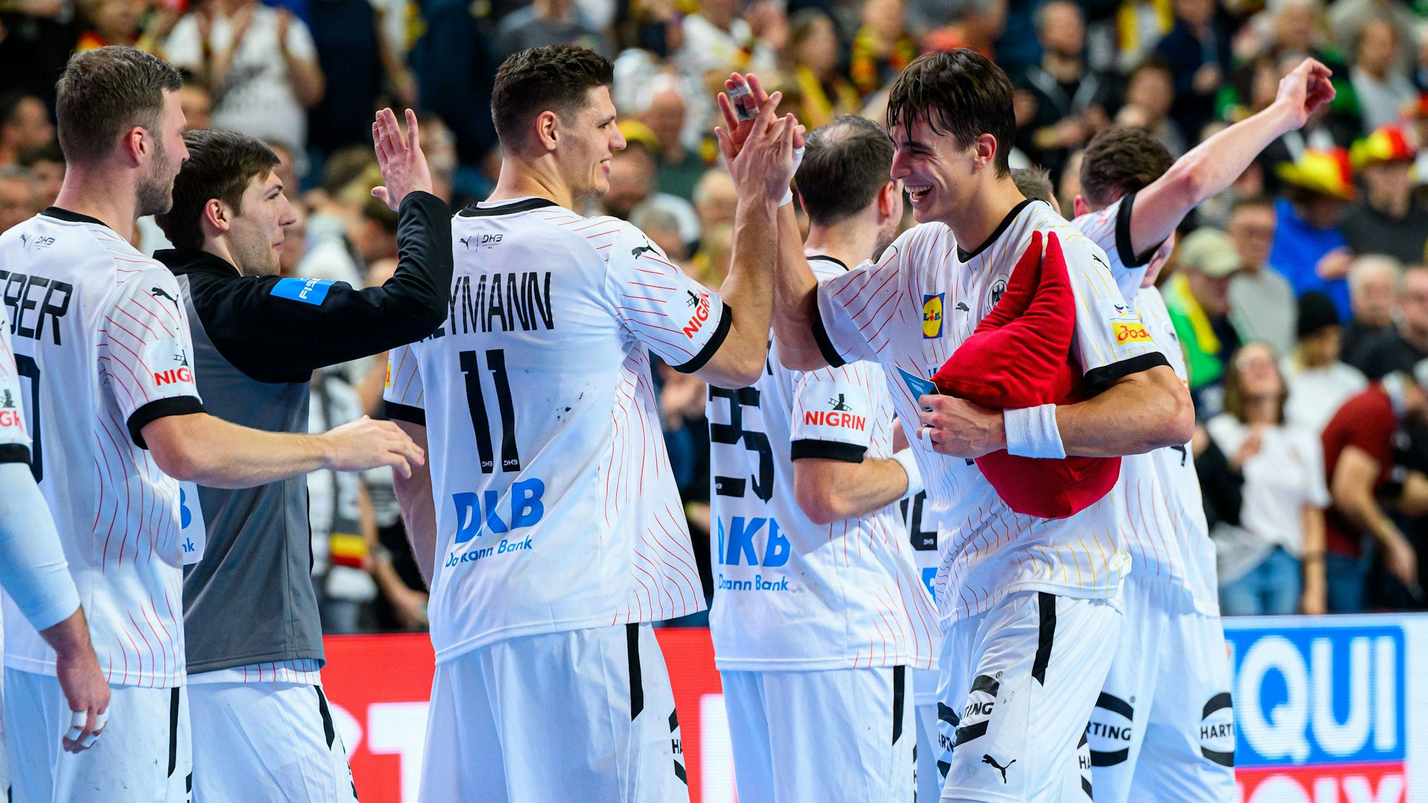 Julian Köster klatscht sich mit dem roten Plüsch-Dom, der Auszeichnung für den Spieler des Spiels mit seinen Kollegen ab.