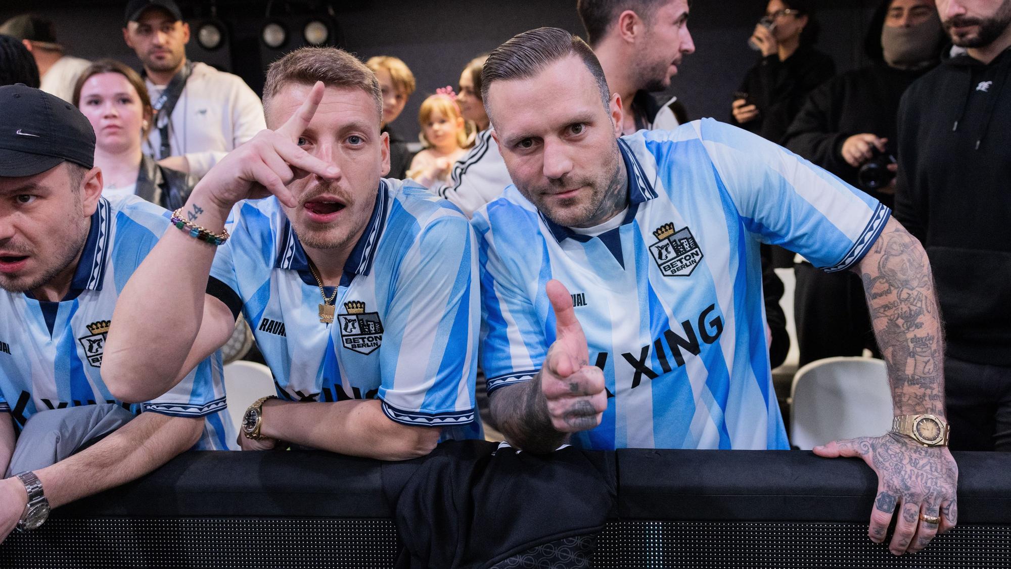 Felix Lobrecht (l), Comedian, und Kontra K, Rapper, stehen als Team-Manager des Teams Beton Berlin an der Bande des Spielfeldrands in der Motorworld. Die neue Kleinfeld-Liga von Mats Hummels und Lukas Podolski, die Baller League, startet in die erste Saison.