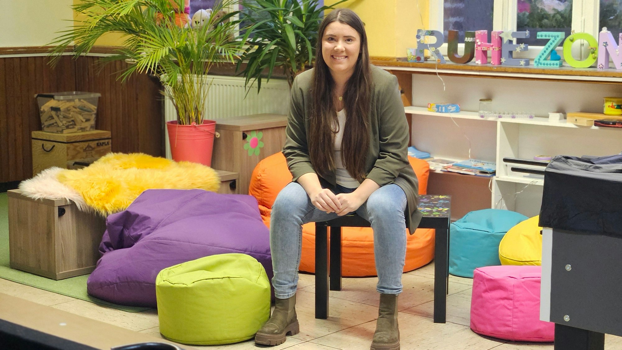 Eine junge Frau sitzt inmitten bunter Sitzkissen.
