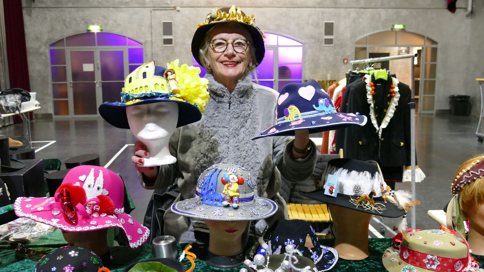 Eine Frau hält bunte Hüte hoch.