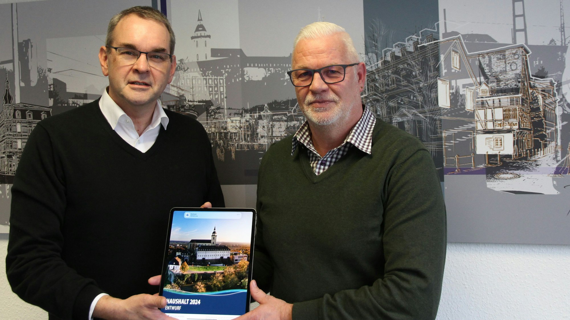 Zwei Männer mit einem Tablet vor einer Grafik mit Siegburger Motiven
