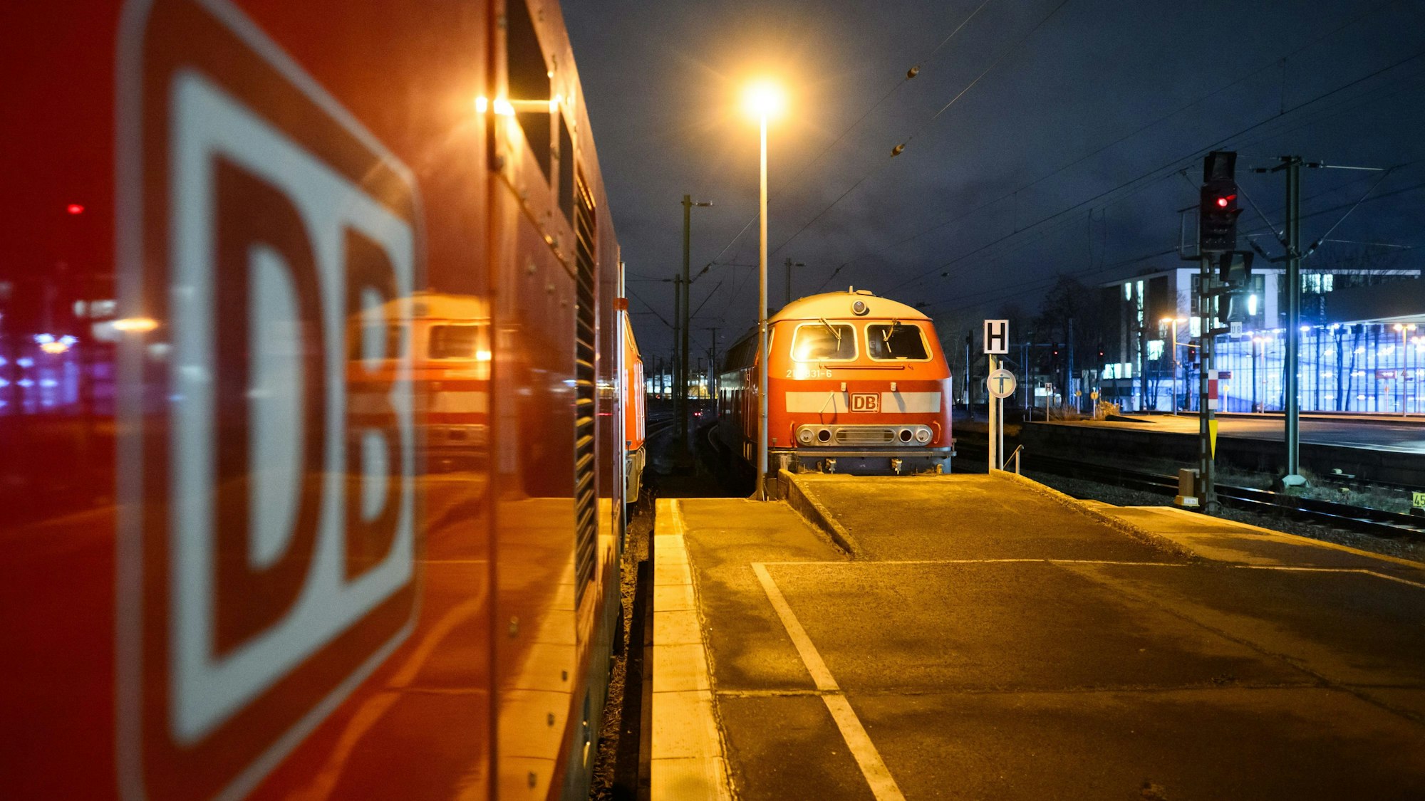 Eine Lok der Deutschen Bahn DB steht im Hauptbahnhof Hannover und spiegelt sich in einem Waggon mit dem DB Logo.