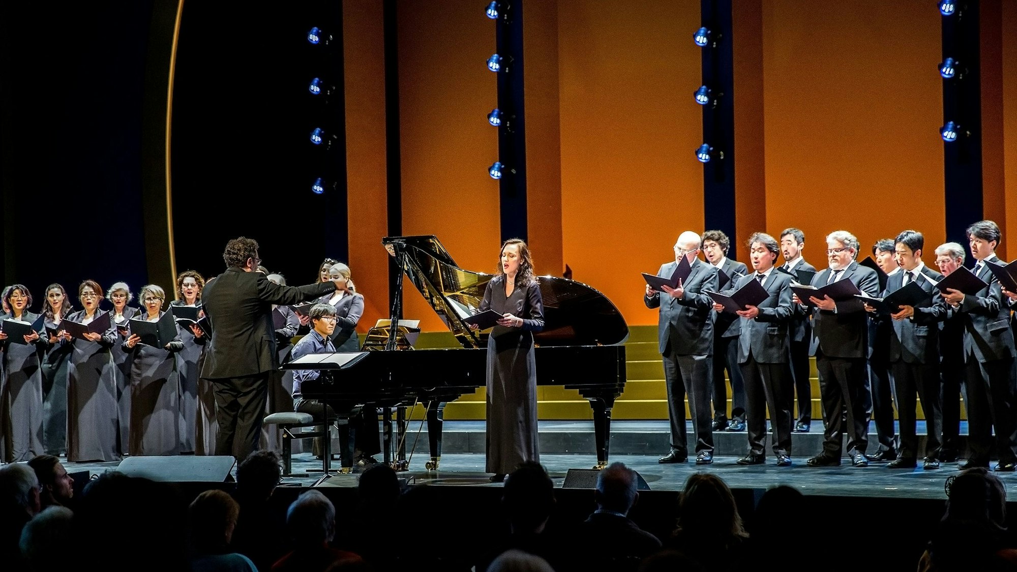 Das Foto zeigt den Chor der Kölner Oper unter der Leitung von Rustam Samedov und Solistin Maria Möller.