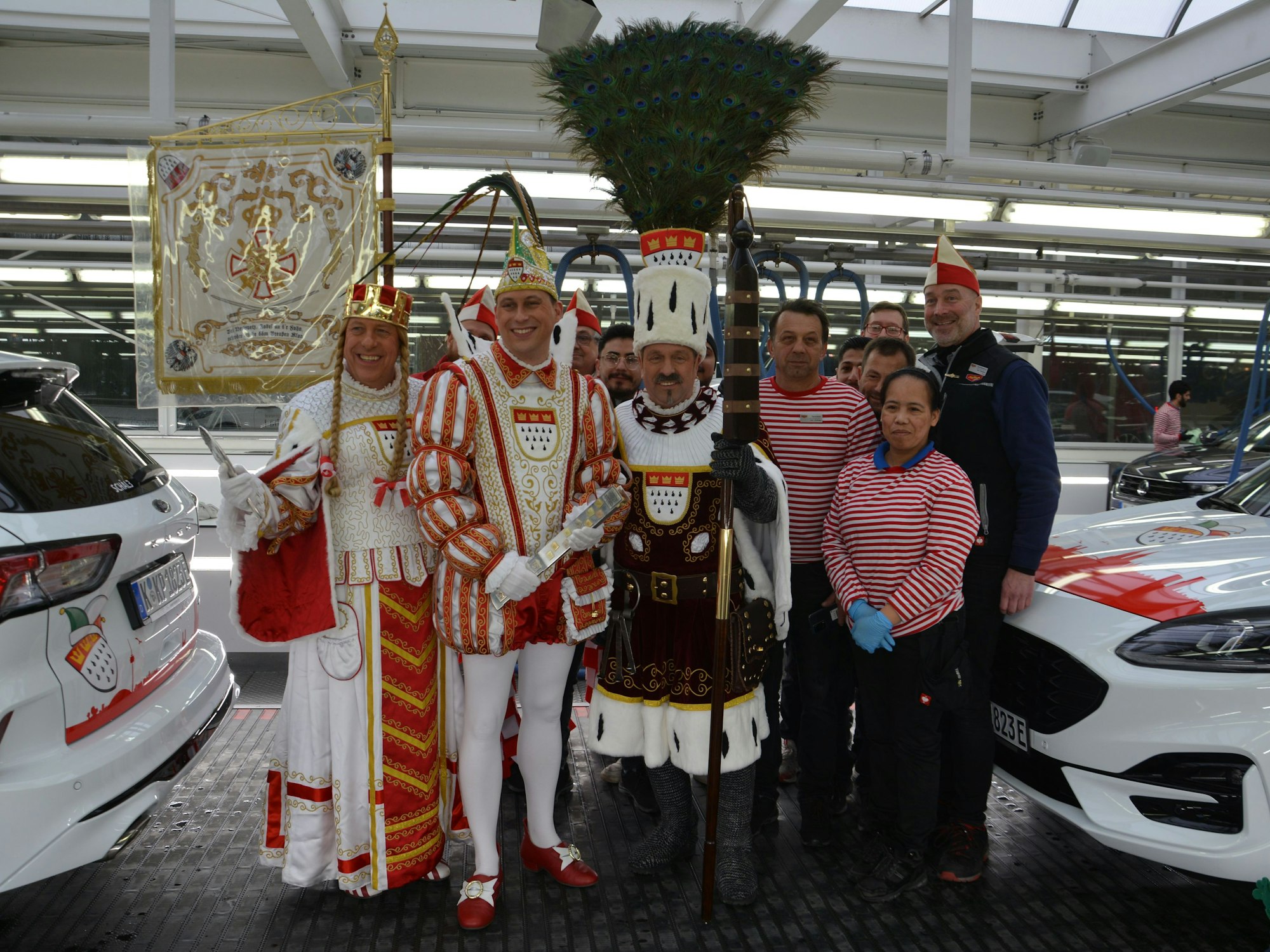 Das Dreigestirn steht mit dem Team der Waschanlage zwischen zwei Autos.