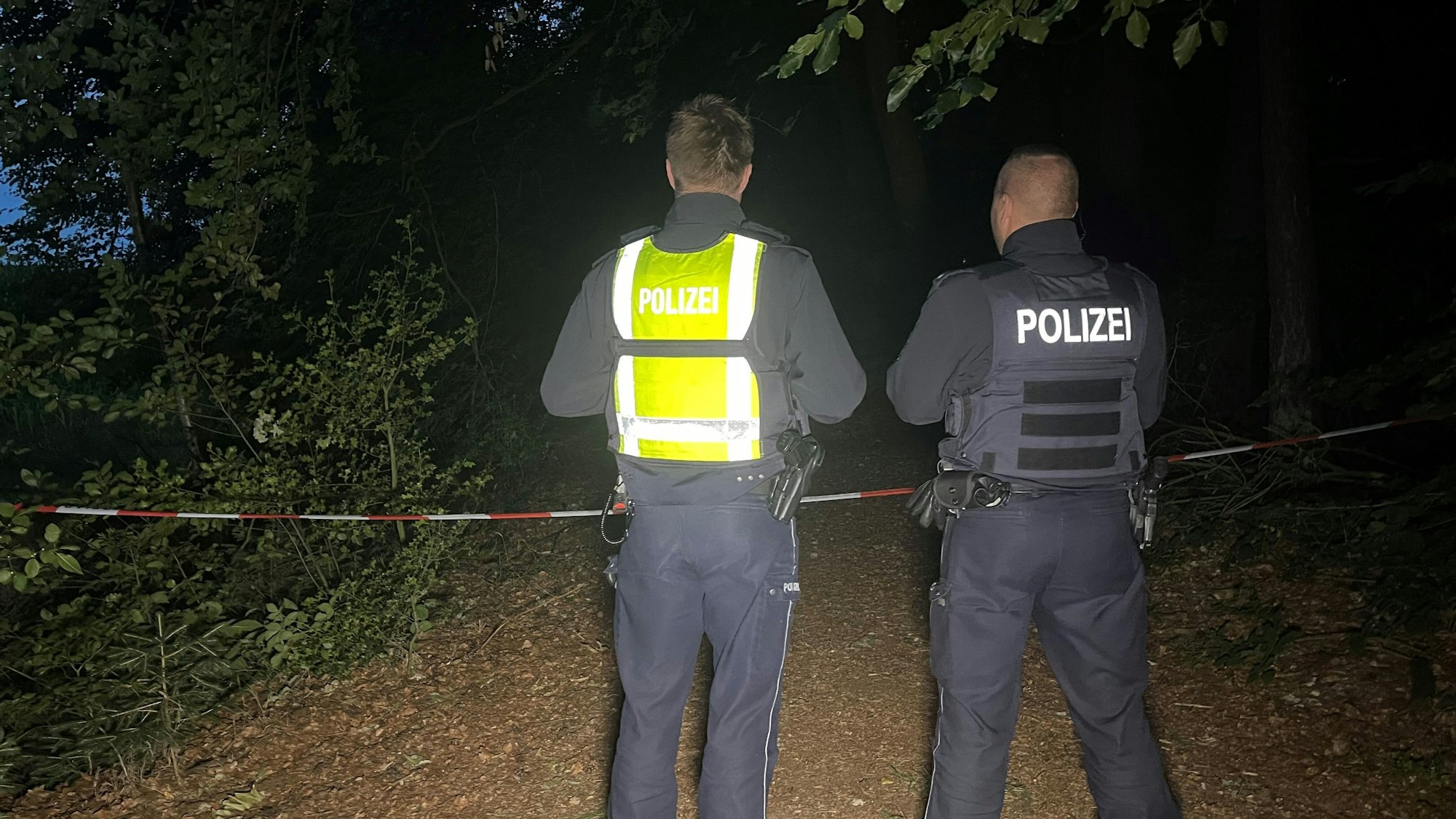 Polizisten stehen an einem abgesperrten Waldstück.