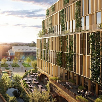 Zwei Gebäudekomplexe mit einer Grünanlage mit Teich und dem Außenbereich einer Gastronomie sind zu sehen.