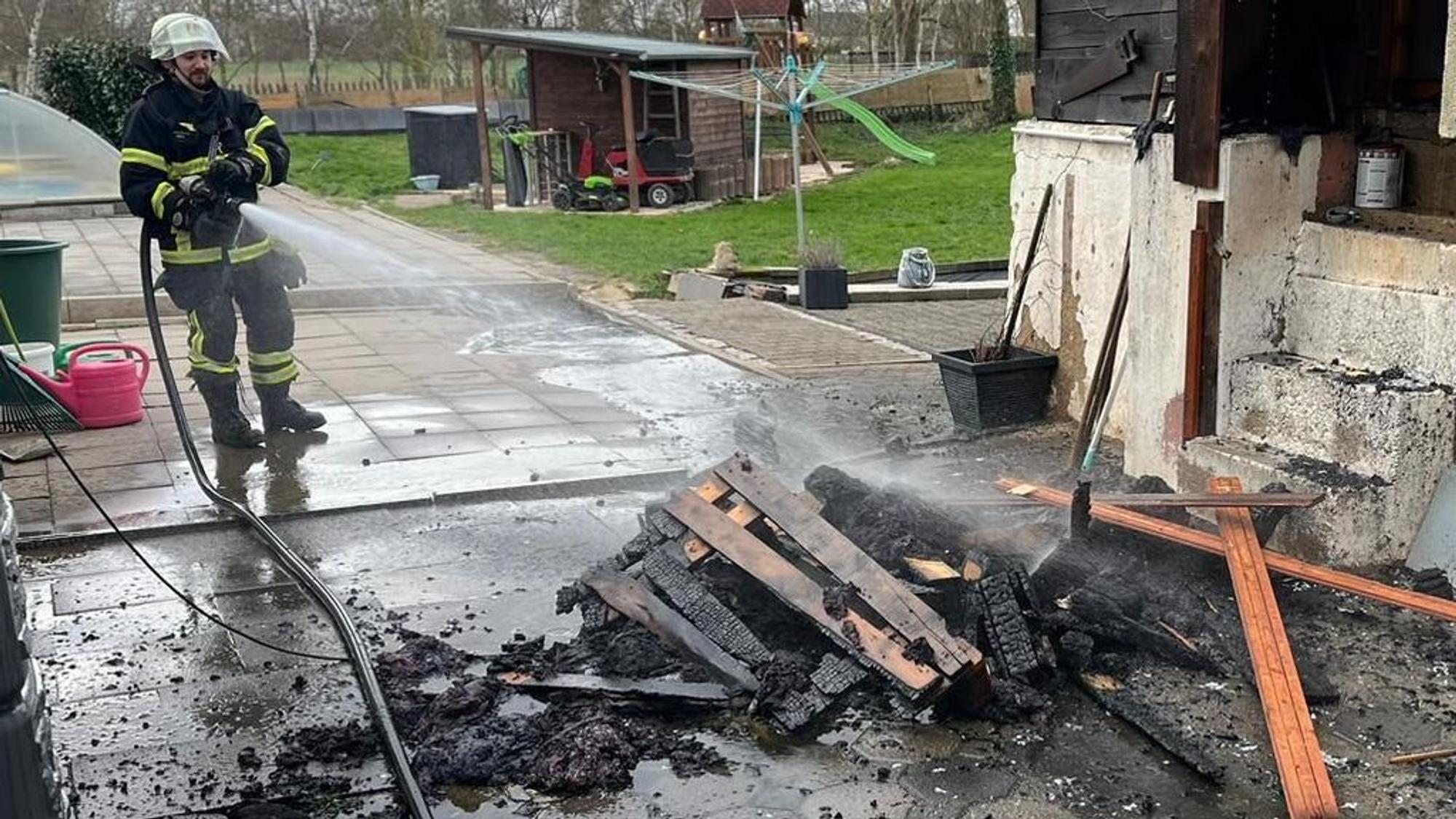 Das Bild zeigt Feuerwehrleute beim Löschen von Holzmöbeln.