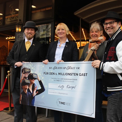 Zwei Männer und drei Frauen vor einem Check mit der Aufschrift „für den 1. Millionsten Gast“