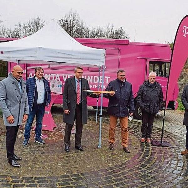 Der damalige Niederkasseler Bürgermeister Stephan Vehreschild und Vertreter von Telekom, Politik und Stadtverwaltung stehen vor einem magentafarbenen Infomobil der Telekom.