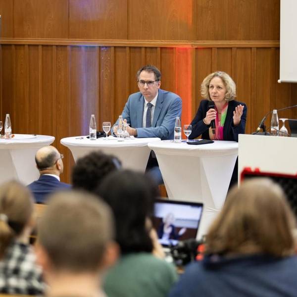 Hörsaal II der Uni Köln ist mit Studierenden und Mitarbeitenden dr Uni Köln gefüllt, vorne sitzen die Vortragenden.