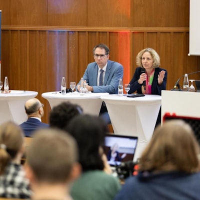 Hörsaal II der Uni Köln ist mit Studierenden und Mitarbeitenden dr Uni Köln gefüllt, vorne sitzen die Vortragenden.