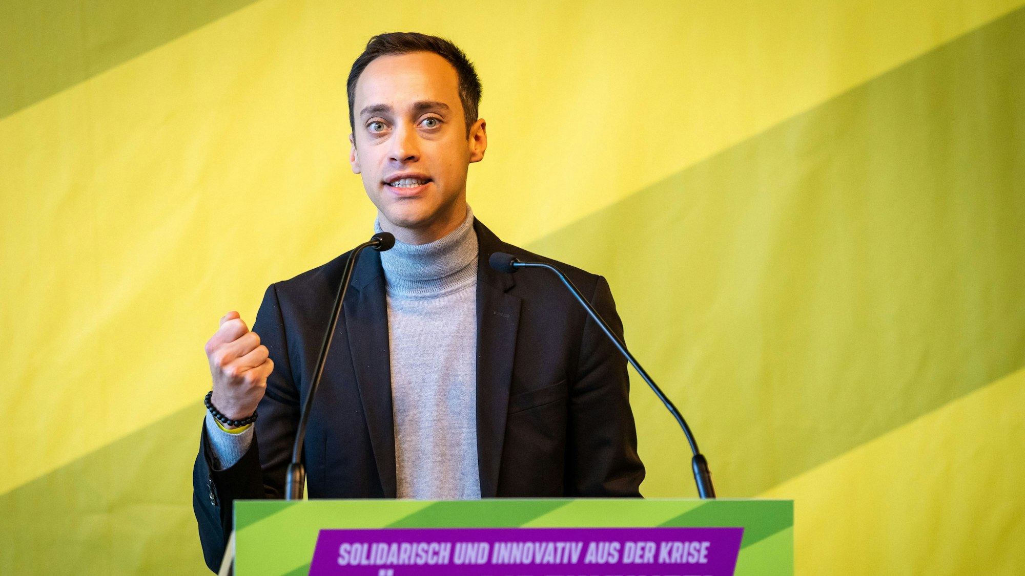 Tim Achtermeyer ist einer der beiden Landesvorsitzenden der NRW-Grünen. Er ist am Rednerpult zu sehen.