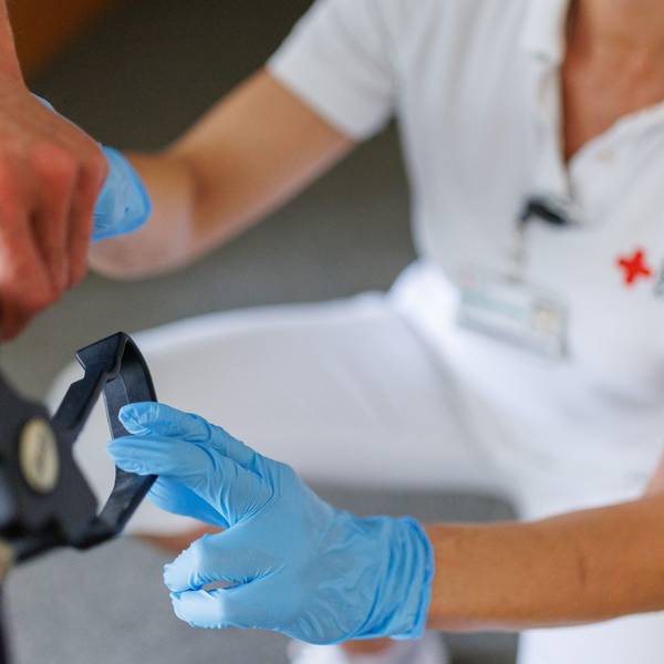 Eine ambulante Pflegefachkraft begleitet einen Bewohner des Betreuten Wohnens mit seiner Gehhilfe durch das Gebäude.